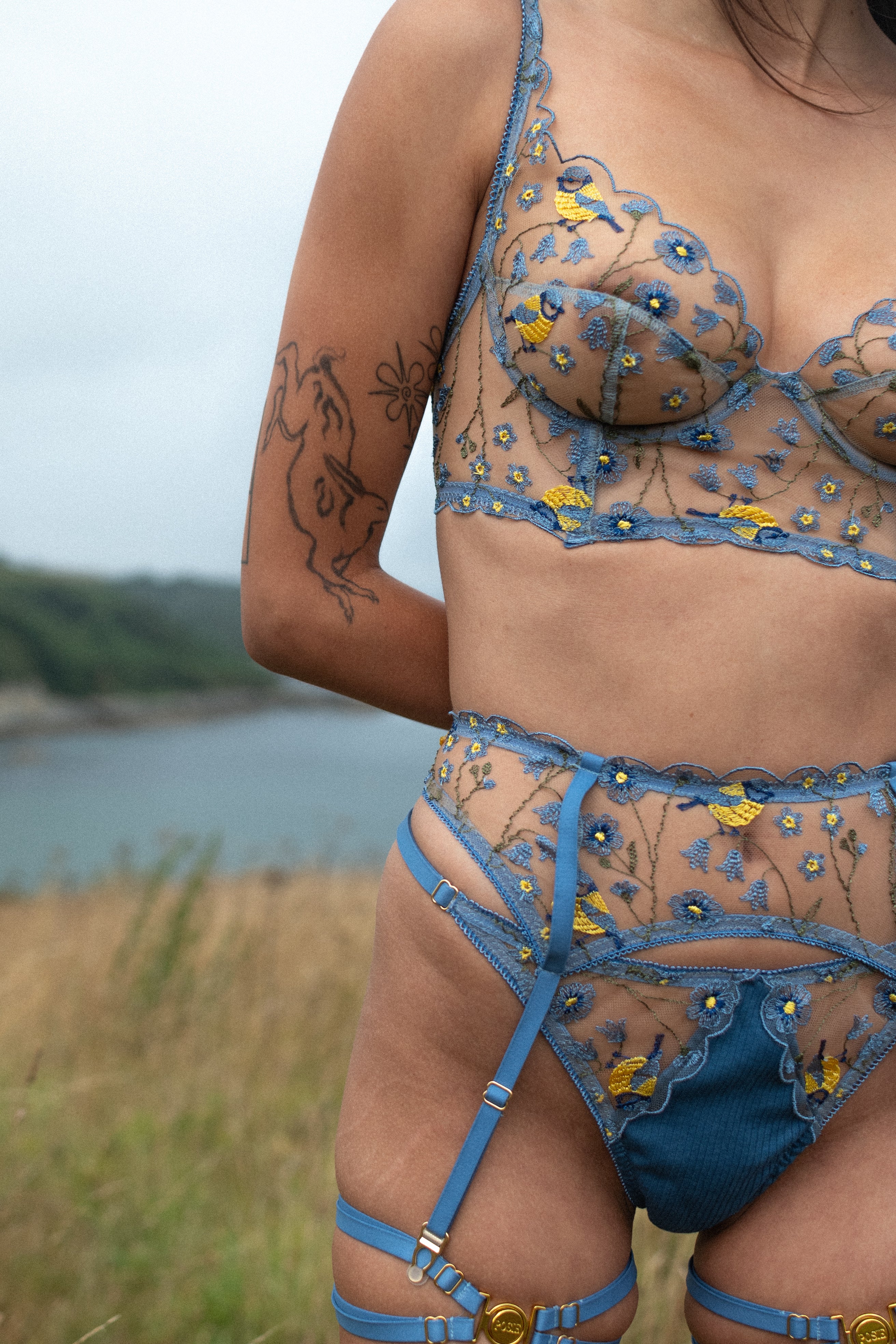 Model wears blue embroidered longline plunge bra, suspender belt and g-string from the Birdsong collection.