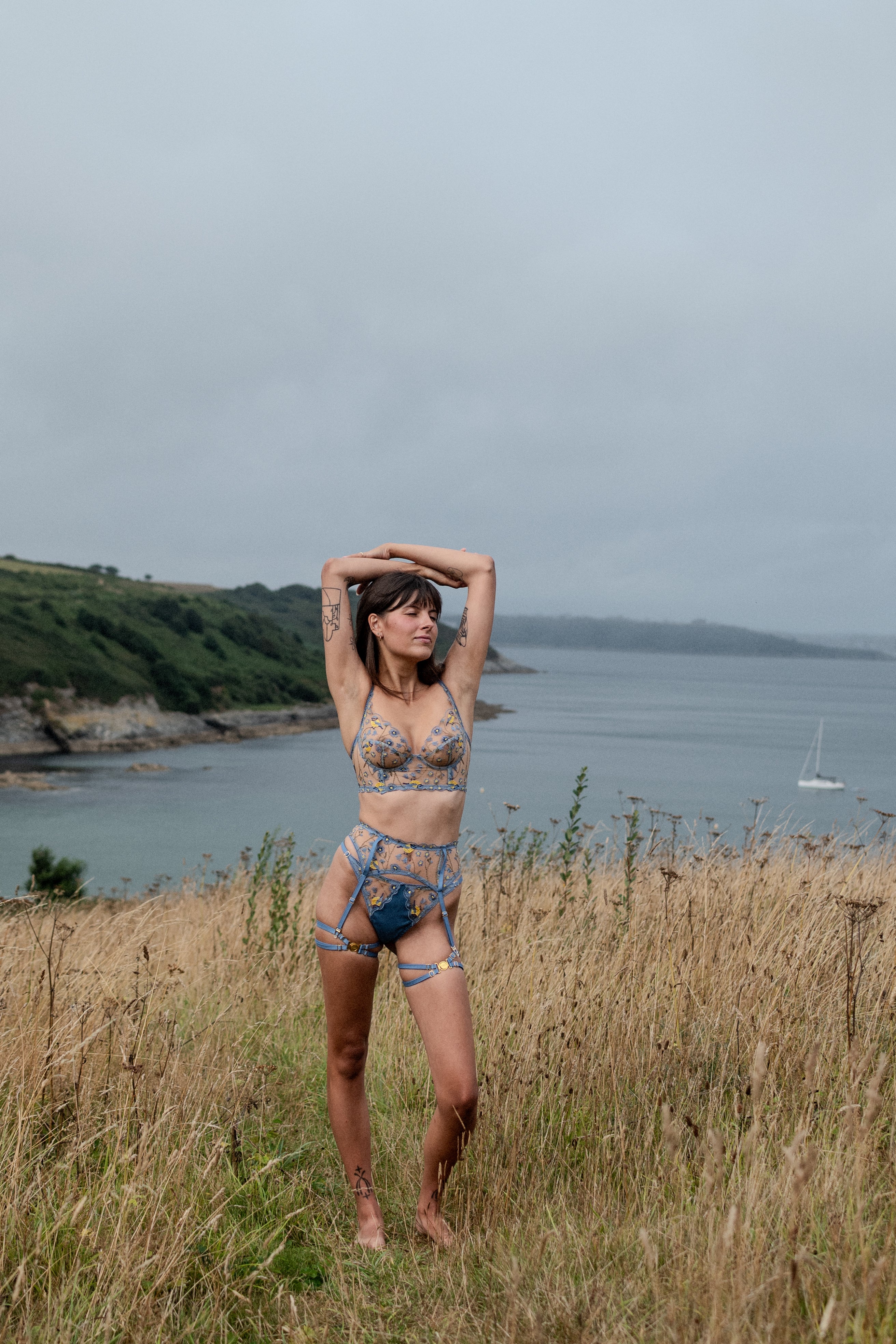 Model wears blue embroidered longline plunge bra, suspender belt and g-string from the Birdsong collection.