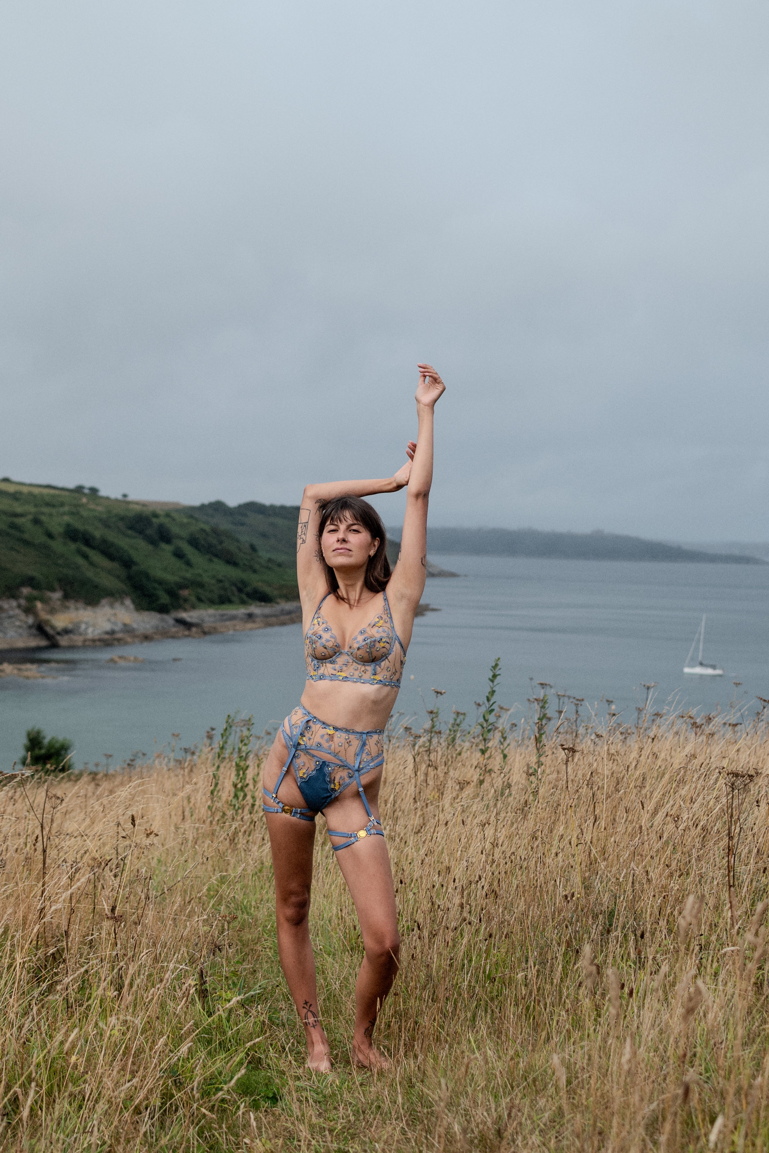 Model wearing embroidered plunge bra, suspender belt and g-string from the Birdsong collection.